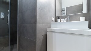 A modern bathroom with a glass shower enclosure, a white sink, and a large mirror.