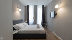 A modern hotel room with a large bed, a bedside table, a chair, and a TV mounted on the wall. - Charming Apartment in Milan's Heart (Milan)