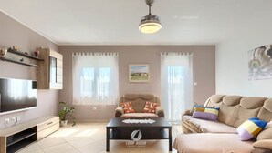A living room with a flat-screen TV, a sofa, a coffee table, and a ceiling fan. - Villa in Galizana With Bubble Bath (Vodnjan)