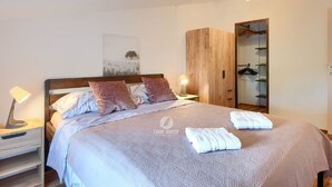 A neatly made bed with a headboard, two bedside lamps, a wooden wardrobe, and a mirror. - Villa in Galizana With Bubble Bath (Vodnjan)