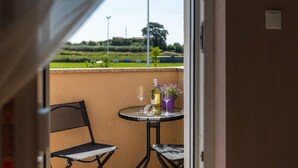 A balcony with a table and chairs, a bottle, and a potted plant. - Villa in Galizana With Bubble Bath (Vodnjan)