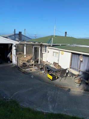 Un garage attenant à une maison, équipé d’un établi, de chaises et d’une brouette.