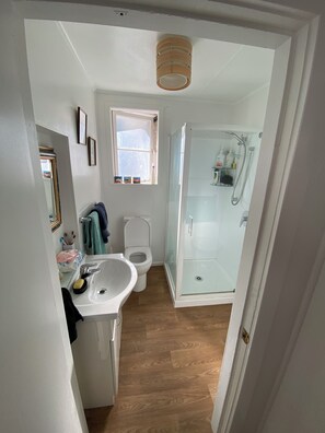 Une petite salle de bain avec un lavabo blanc, des toilettes et une douche à parois de verre.