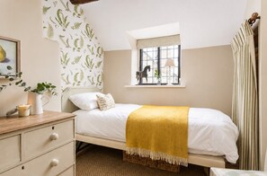 Ein Schlafzimmer mit Bett, Fenster mit Blick, Nachttisch mit Kerze und Pflanze.