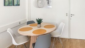 Une table ronde avec une plante, quatre chaises et des œuvres d’art accrochées au mur.