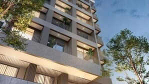 Un immeuble de grande hauteur doté de nombreux balcons, présentant un style architectural moderne et se dressant sous un ciel dégagé.