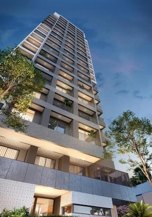 En hög byggnad med flera balkonger, en modern arkitektonisk stil och en klar himmel.