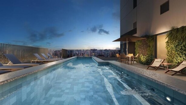Une piscine sur le toit, agrémentée de chaises longues, offrant une vue sur le paysage urbain et présentant une façade de bâtiment moderne.
