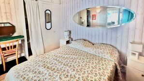 A bedroom with a floral bedspread, a wooden chair, a desk, a mirror, and a bedside table. - Seaside apartment - Cap Ferret - Bassin d' Arcachon (Lège-Cap-Ferret)