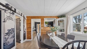A dining area with a wooden wall, a large table, and chairs.