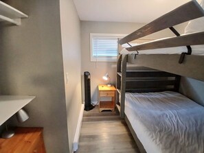 A bunk bed room with a desk and chair, a heater, and a window with blinds.