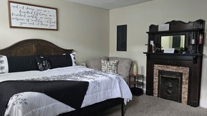 A bedroom with a large bed, a fireplace, a sofa, and a wall-mounted TV. - Charming 2-bedroom house in close proximity to the YUM Ctr, the Downs, etc. (Louisville)