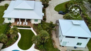 A two-story house with a swimming pool, a covered patio, and a well-maintained lawn.