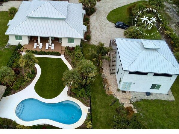 A two-story house with a swimming pool, a covered patio, and a well-maintained lawn. - Indian River Retreat  - Main House and Cottage (Jensen Beach)
