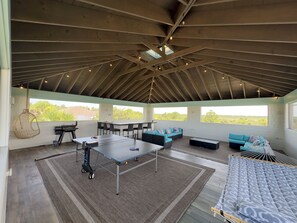 An indoor-outdoor space with a ping pong table, seating area, and a grill. - Indian River Retreat  - Main House and Cottage (Jensen Beach)