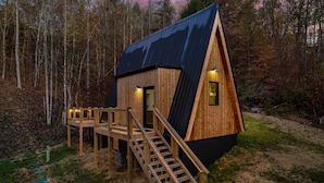 Una cabaña de madera con techo inclinado, una terraza de madera y una escalera que conduce a la entrada.