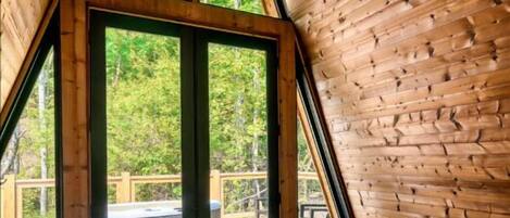 Eine dreieckige Holzhütte mit einer großen Glastür, die auf eine Außenterrasse führt.