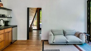 Un interior moderno con área de cocina, un sofá y techo de madera.