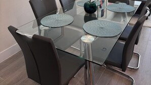 A modern dining area with a glass table, black chairs, and a central decorative vase. - 3-bedroom house in Orlando close to Disney with Customizable children's room (Clermont)