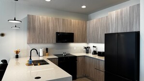 A modern kitchen with a central island, black appliances, and wooden cabinetry. - 3-bedroom house in Orlando close to Disney with Customizable children's room (Clermont)