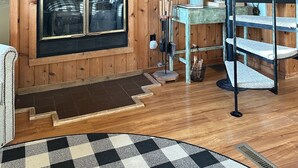 Un intérieur en bois avec une cheminée, un escalier en colimaçon et une grande fenêtre.