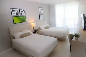 A hotel room with two beds, a desk, a chair, and artwork on the walls.