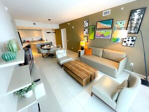 A modern living room with a sofa, coffee table, and a dining area. - Ocean View Apt on the Beach 2 Bedroom 2 Bath. (Hollywood)