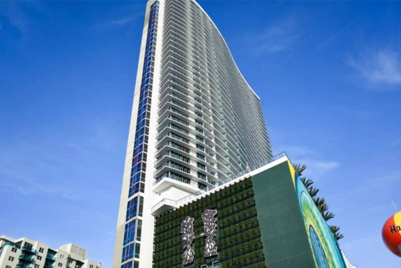 Un edifici alt i modern amb una façana corbada i un logotip destacat a la part inferior.