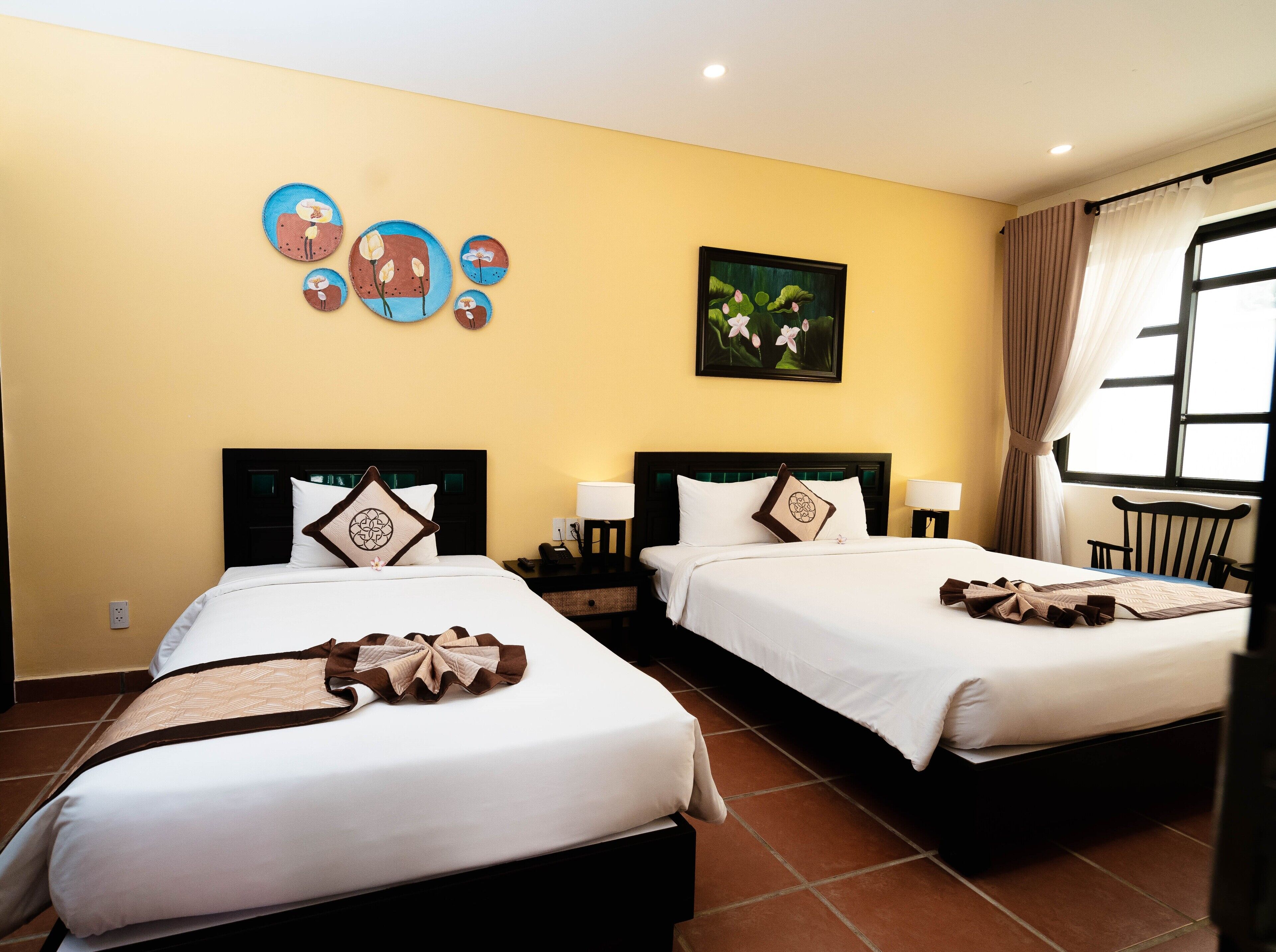 Una habitación de hotel con dos camas, un cuadro en la pared y una ventana con cortinas.