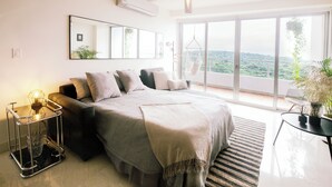 Quarto moderno com uma cama grande, uma cadeira suspensa e vista para o exterior.