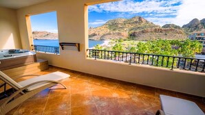 A balcony with a hot tub, lounge chairs, and a view of a mountainous landscape.