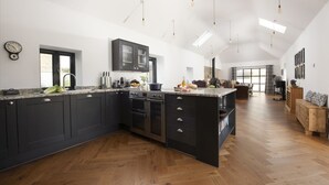 A modern kitchen with dark cabinetry, a large island, and a herringbone wood floor.