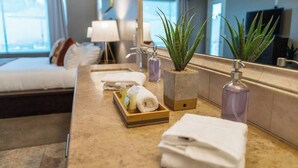 A hotel bathroom with a marble countertop, a sink, two potted plants, a soap dispenser, and a tray with towels. - Pueblo Viejo (Scottsdale)