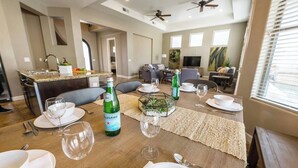A dining area with a wooden table set for a meal, a bottle of wine, and a TV in the background. - Pueblo Viejo (Scottsdale)