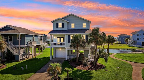 A two-story house with a front porch, a small pool, and a well-maintained lawn.