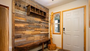 A wooden wall with built-in shelves and hooks, a bench, and a wooden sculpture.