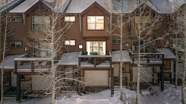 A multi-story residential building with a central entrance, multiple balconies, and a garage.