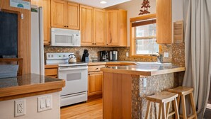 A kitchen with wooden cabinets, a microwave, a stove, and a granite countertop.