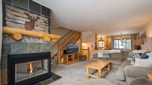 A cozy living room with a fireplace, a wooden TV stand, and a comfortable seating area.