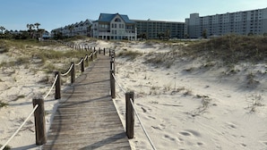 A wooden boardwalk leading to a beachfront hotel with multiple balconies and a modern design. - Welcome to SEA-Nanigans. Unit #1366. 
A charming condo with Gulf Views. (Gulf Shores)