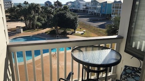 A balcony with a pool, outdoor furniture, and a view of a residential area with houses and a beach. - Welcome to SEA-Nanigans. Unit #1366. 
A charming condo with Gulf Views. (Gulf Shores)