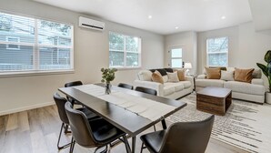 A modern living room with a dining area, large windows, and a neutral color palette. - El Paso Executive Suites | Pet Friendly NEW BUILD (Colorado Springs)