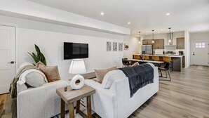 A modern living room with a sofa, a coffee table, and a TV mounted on the wall. - El Paso Executive Suites | Pet Friendly NEW BUILD (Colorado Springs)