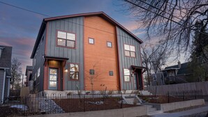 A two-story house with a grey exterior and orange siding, featuring a front entrance with steps and a small garden area. - El Paso Executive Suites | Pet Friendly NEW BUILD (Colorado Springs)