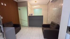 A reception area with a reception desk, two sofas, a staircase, and a door leading to another room. - Pousada Princesa do Sertão (Piranhas)