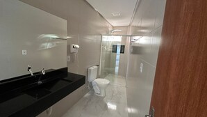A modern bathroom with a black countertop, a toilet, and a glass shower enclosure. - Pousada Princesa do Sertão (Piranhas)