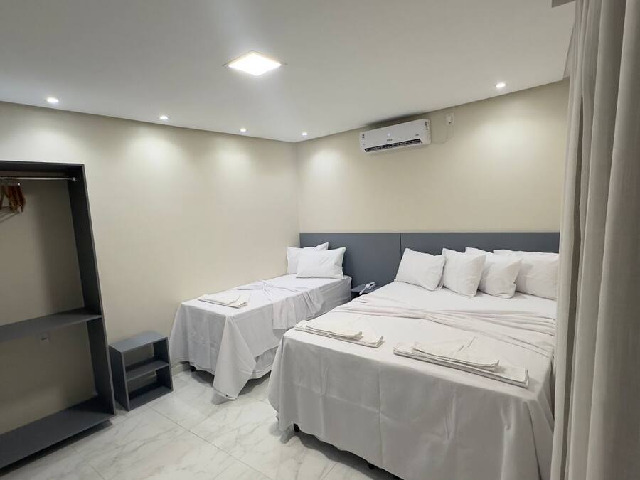 Habitación de hotel con dos camas, un armario y aire acondicionado instalado en el techo.