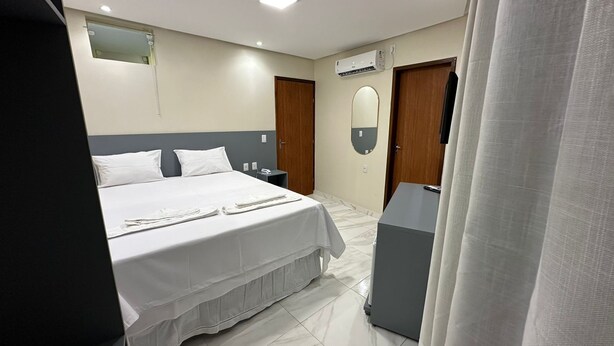 A hotel room with a bed, bedside tables, an air conditioning unit, and a mirror. - Pousada Princesa do Sertão (Piranhas)