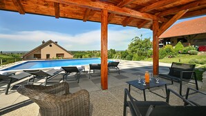 Un área de piscina al aire libre con sillones de descanso y una pérgola.