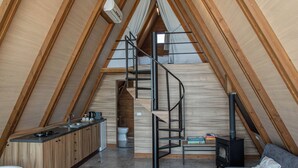 Een moderne loft slaapkamer met een schuine plafond, een ingebouwde keukenhoek, een trap en een gezellige zithoek.